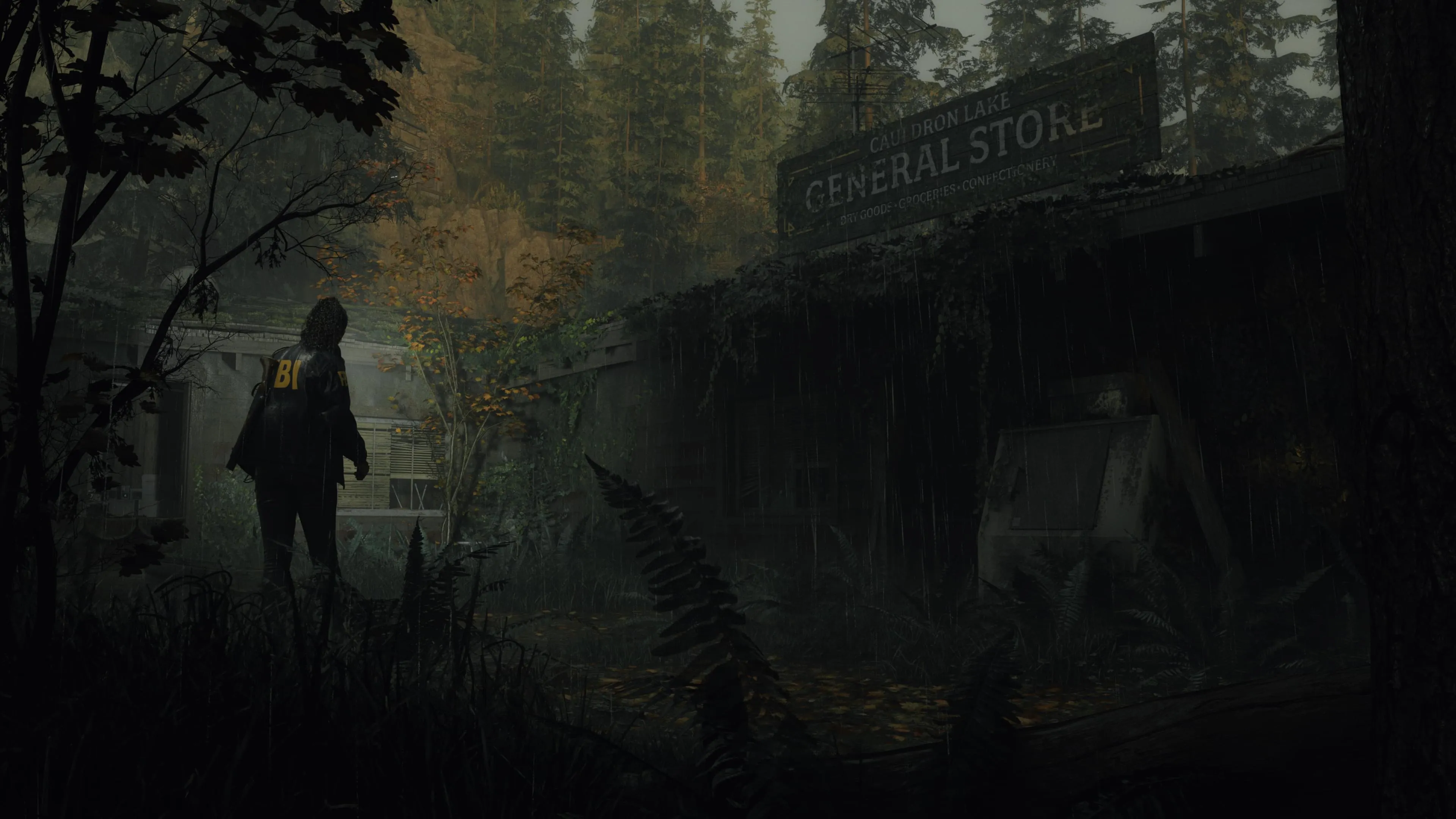 Alan Wake 2: Saga Anderson steht vor dem Gemischtwarenladen in einem bewaldeten Ort.